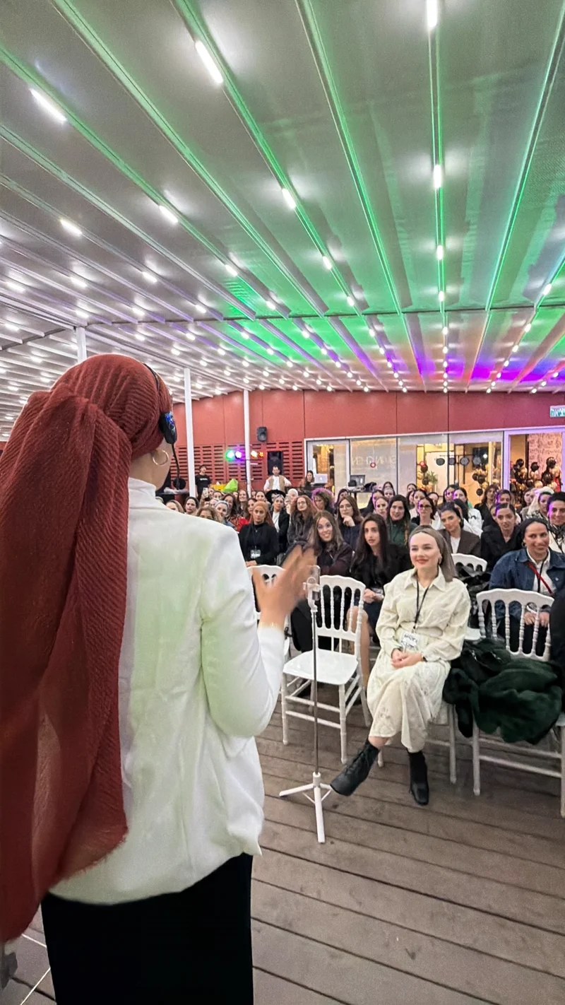 סיון חן מרצה על במה בכנס בוגרות הענף שהרימה, מול קהל המשתתפות